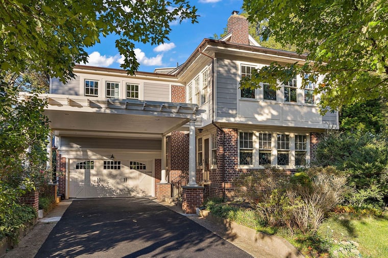 A home addition sits upon a two-story home with attached garage, shuttered windows, and shaded front yard in a residential neighborhood in Delaware
