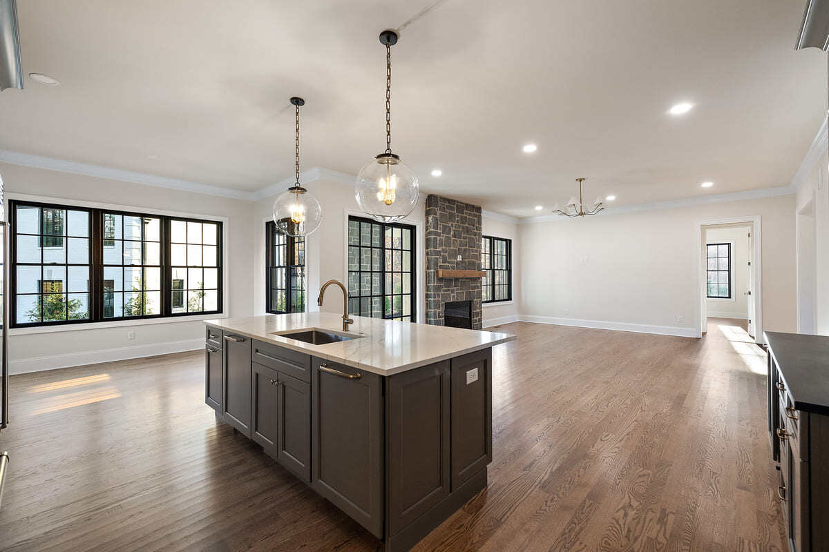 Bulb pendant lights above island in DE custom home kitchen by Bromwell Construction with open-concept dining space in back