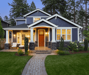 Blue two-story home with shake siding, stone veneer, and white trim