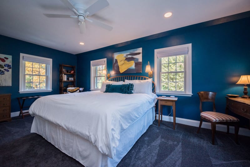 Blue bedroom with three windows and ceiling fan with recessed lighting