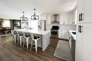 Modern kitchen with white brick backsplash, white cabinets, stainless steel appliances, and bar seating at center island