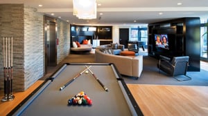 Home game room with wood and carpeted flooring, billiards table, crescent-shaped couch, and entertainment center with TV