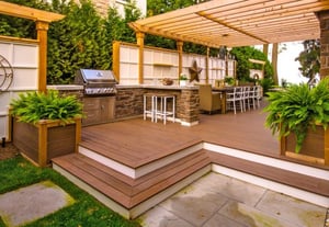 Backyard area with custom wooden deck, pergola, outdoor kitchen area, and bar seating