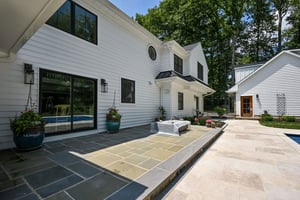 Rear custom home exterior with black window trim and stone patio