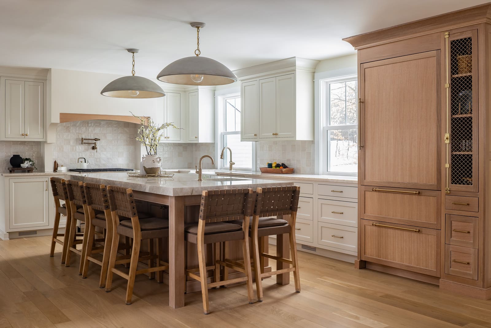 Bright kitchen remodel with large island, white cabinetry, wood accents, pendant lights, and built-in refrigerator.
