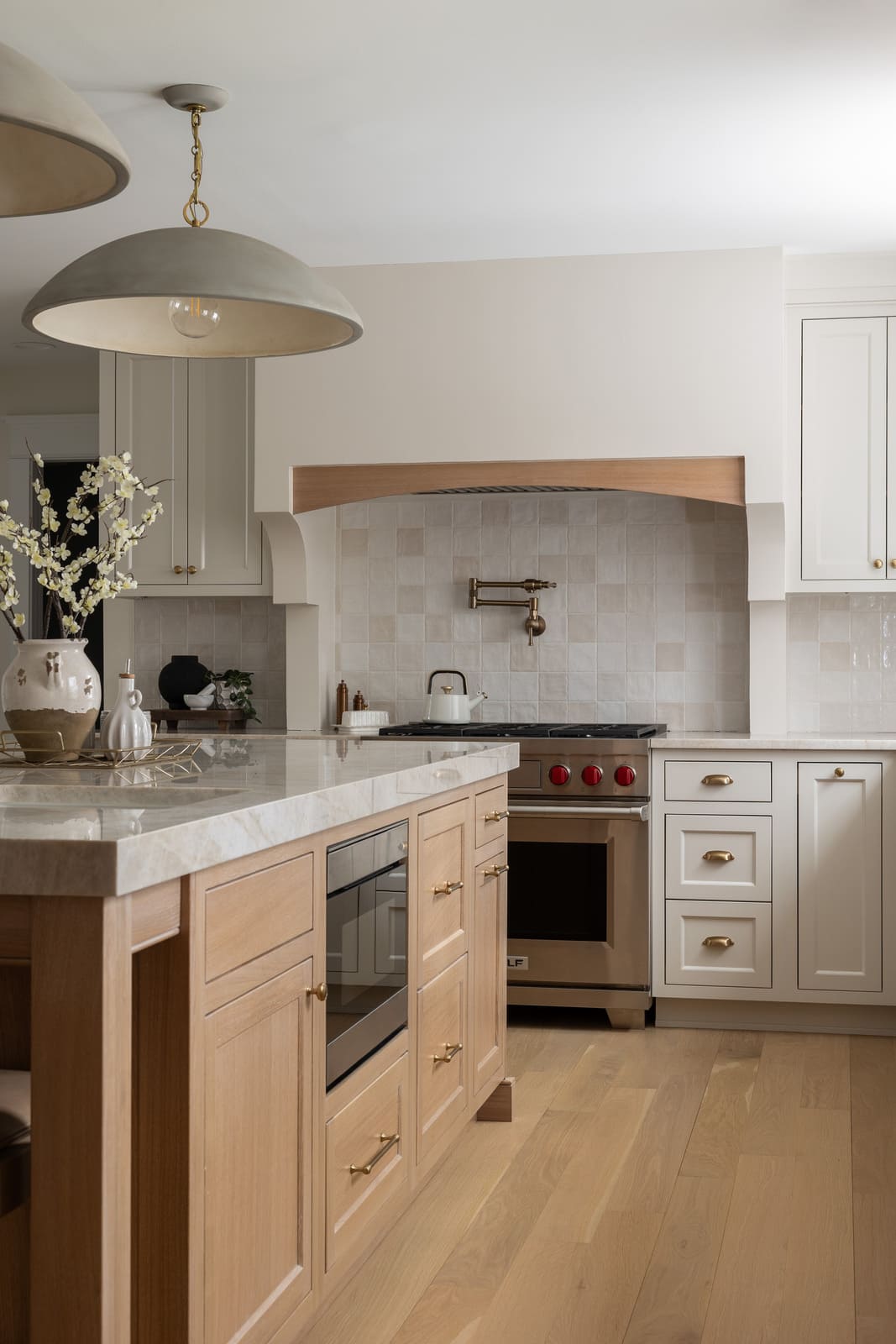 Kitchen remodel with wood island, marble countertop, white cabinets, pendant lights, and tiled range alcove.
