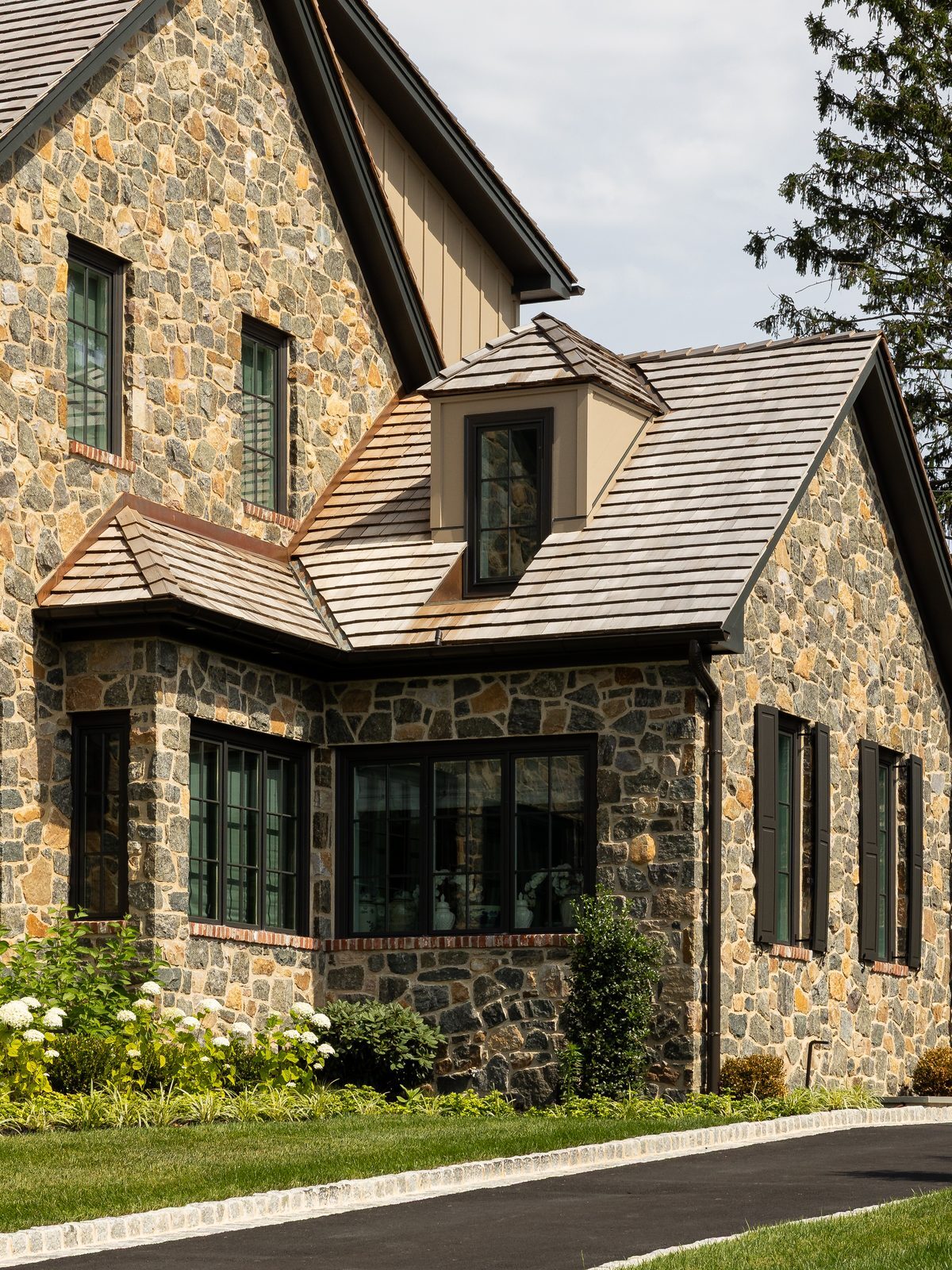 Close-up daytime view of stone gable with shuttered windows and lush hydrangeas