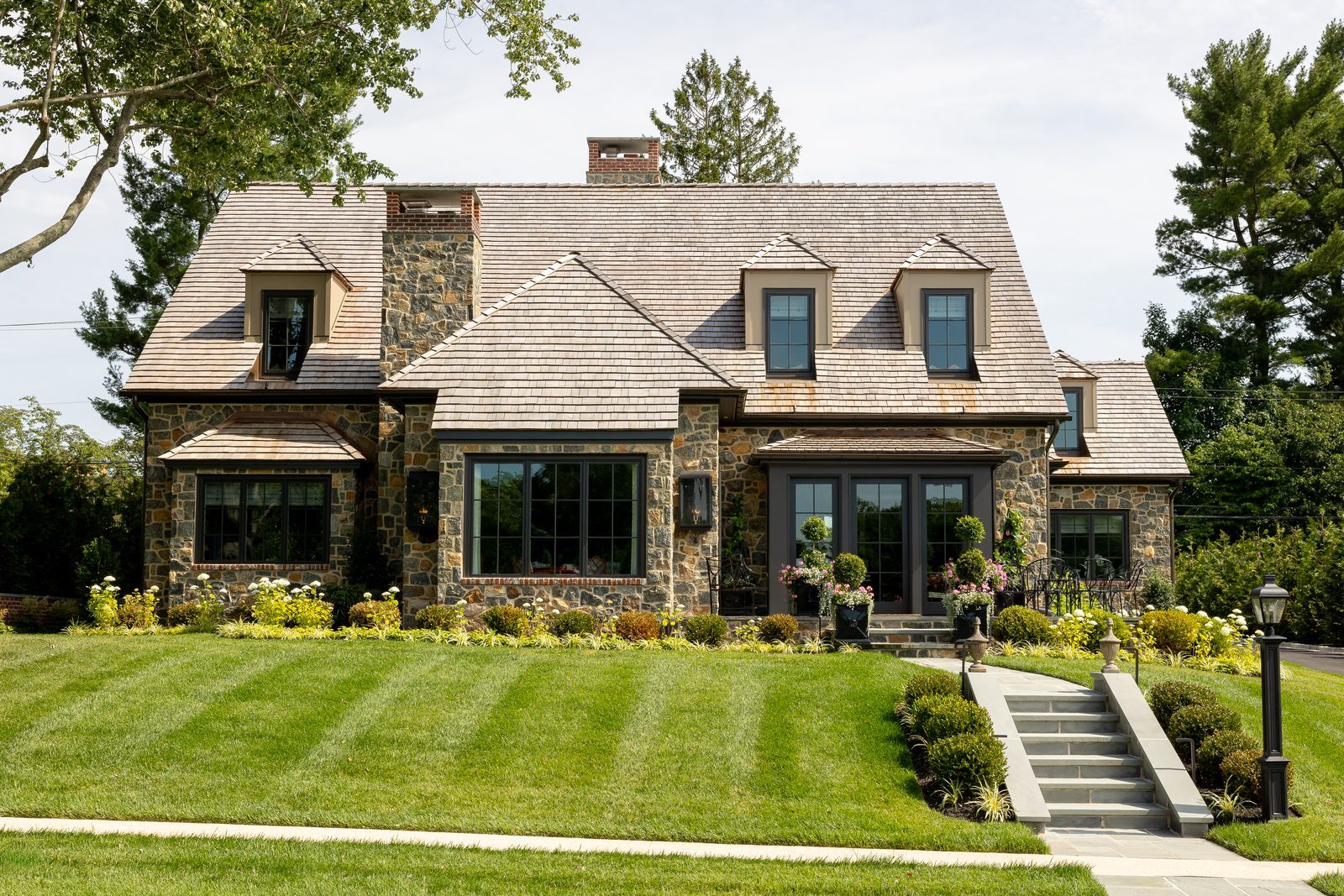 Front-facing daytime view of stone home with bluestone walkway and green lawn
