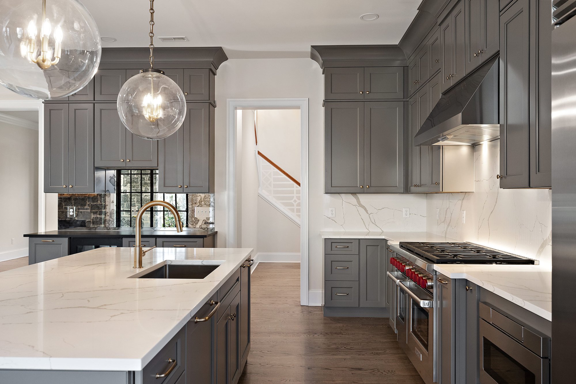 Beautiful new kitchen with stone backsplash, Wolf range, and warm grey cabinets by Bromwell Construction – DE and PA Custom Home Builder and Remodeler