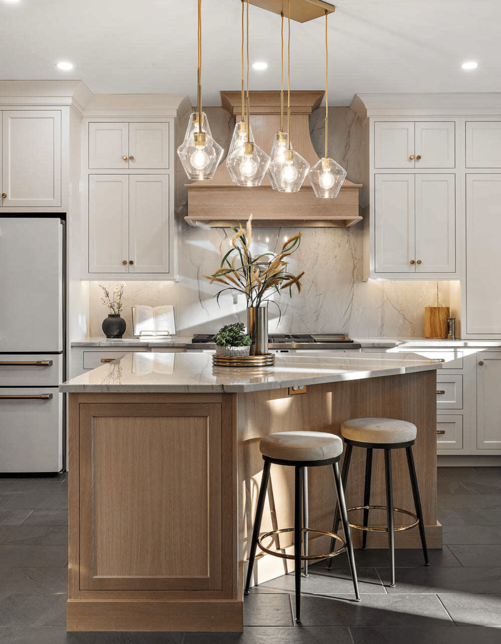 Warm kitchen with light wood island and beautiful brass pendant lights
