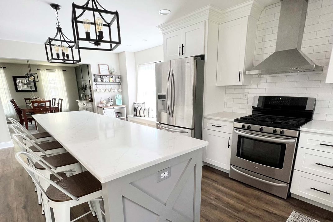 Delaware area kitchen with white cabinets, stainless appliances, large island, and pendant lights