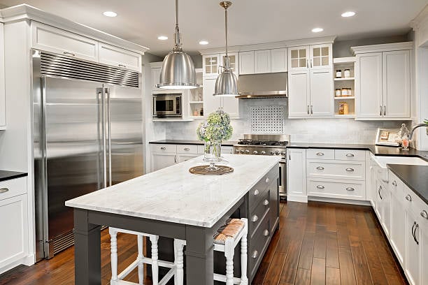 Delaware kitchen with white cabinets, marble island, stainless appliances, and hardwood floors