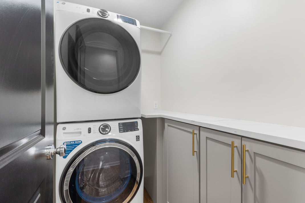 Door opening to remodeled laundry room area with gray shaker cabinets