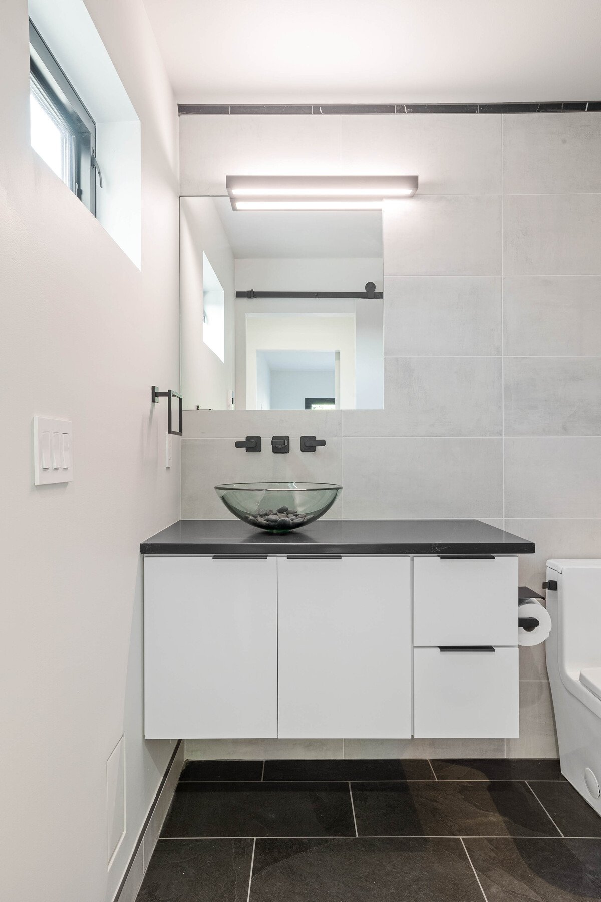 Floating bathroom vanity in Delaware custom home with glass vessel sink and black fixtures