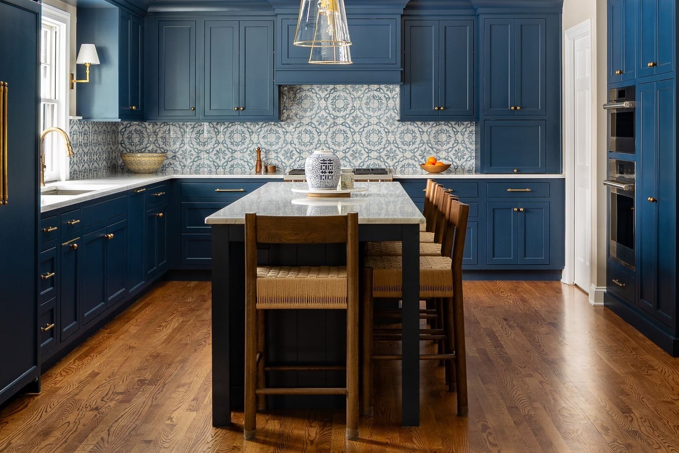 Full remodeled kitchen with navy cabinets, marble island, brass pendants, patterned tile, and wood floors. Full remodeled kitchen with navy cabinets, marble island, brass pendants, patterned tile, and wood floors.