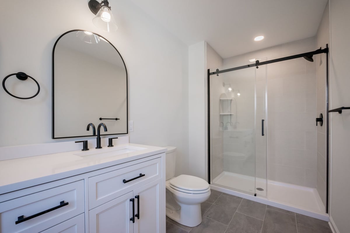 Glass light fixture above mirror in Wilmington, DE bathroom remodel with recessed lighting in shower