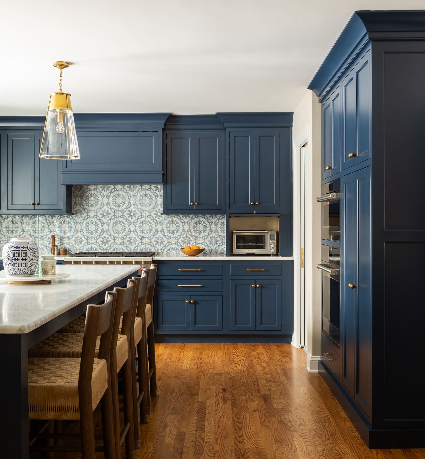 Remodeled kitchen with navy cabinets, marble island, patterned tile, and open appliance garage.