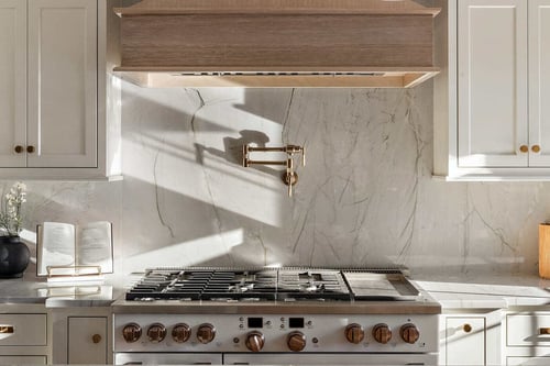 Slab backsplash with pot filler behind stove with brass fixtures in Delaware kitchen remodel by Bromwell Construction
