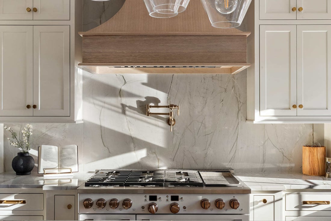 Slab backsplash with pot filler behind stove with brass fixtures in Delaware kitchen remodel by Bromwell Construction