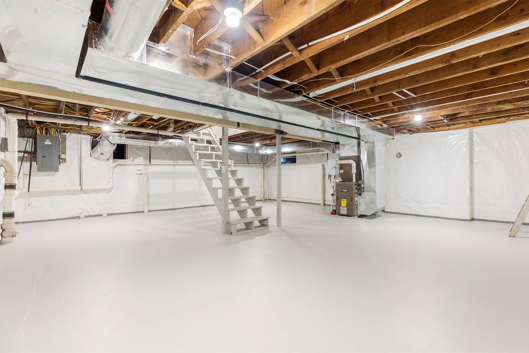 Unfinished basement with exposed beams and white epoxy floor in the Delaware area