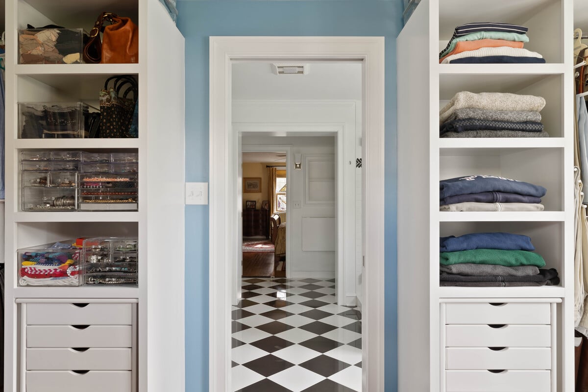 Walk-in closet with vertical built-in shelving with black and white square floor tile in Delaware home addition by Bromwell Construction