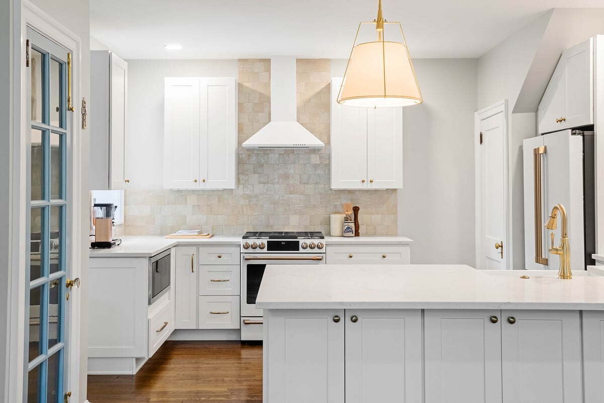 White kitchen cabinets and pendant light above island with sink in Delaware home remodel by Bromwell Construction