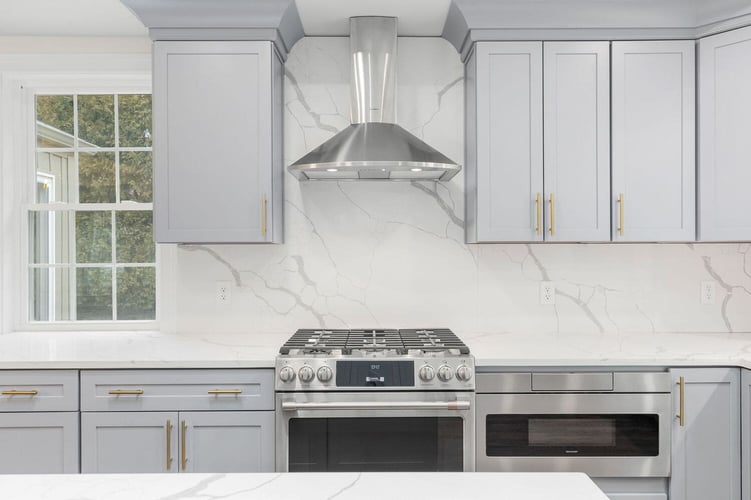 light gray shaker cabinets in modern kitchen remodel with stainleses steel range hood and oven