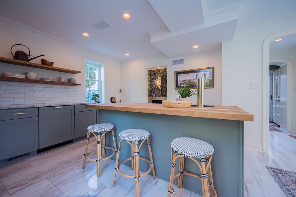 Modern kitchen remodel with blue-green cabinets and island with seating beneath recessed lighting