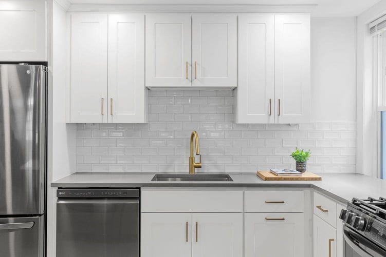 White shaker cabinets in kitchen remodel with brass pulls