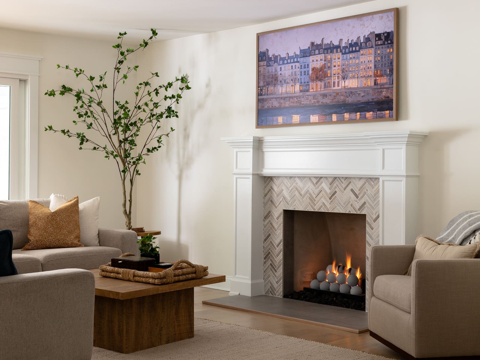 Bright living room with white fireplace, herringbone tile surround, wood coffee table, and neutral seating.