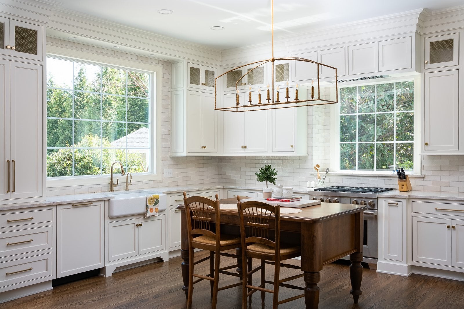 White kitchen with wood island, brass hardware, and linear chandelier in Wilmington, DE