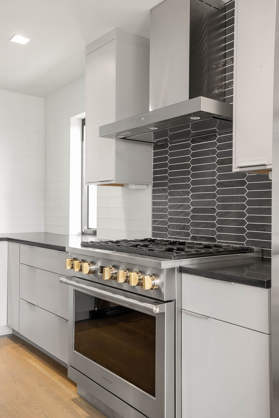 High-end stainless steel oven range and hood with elongated hexagon backsplash behind in Wilmington, DE custom kitchen
