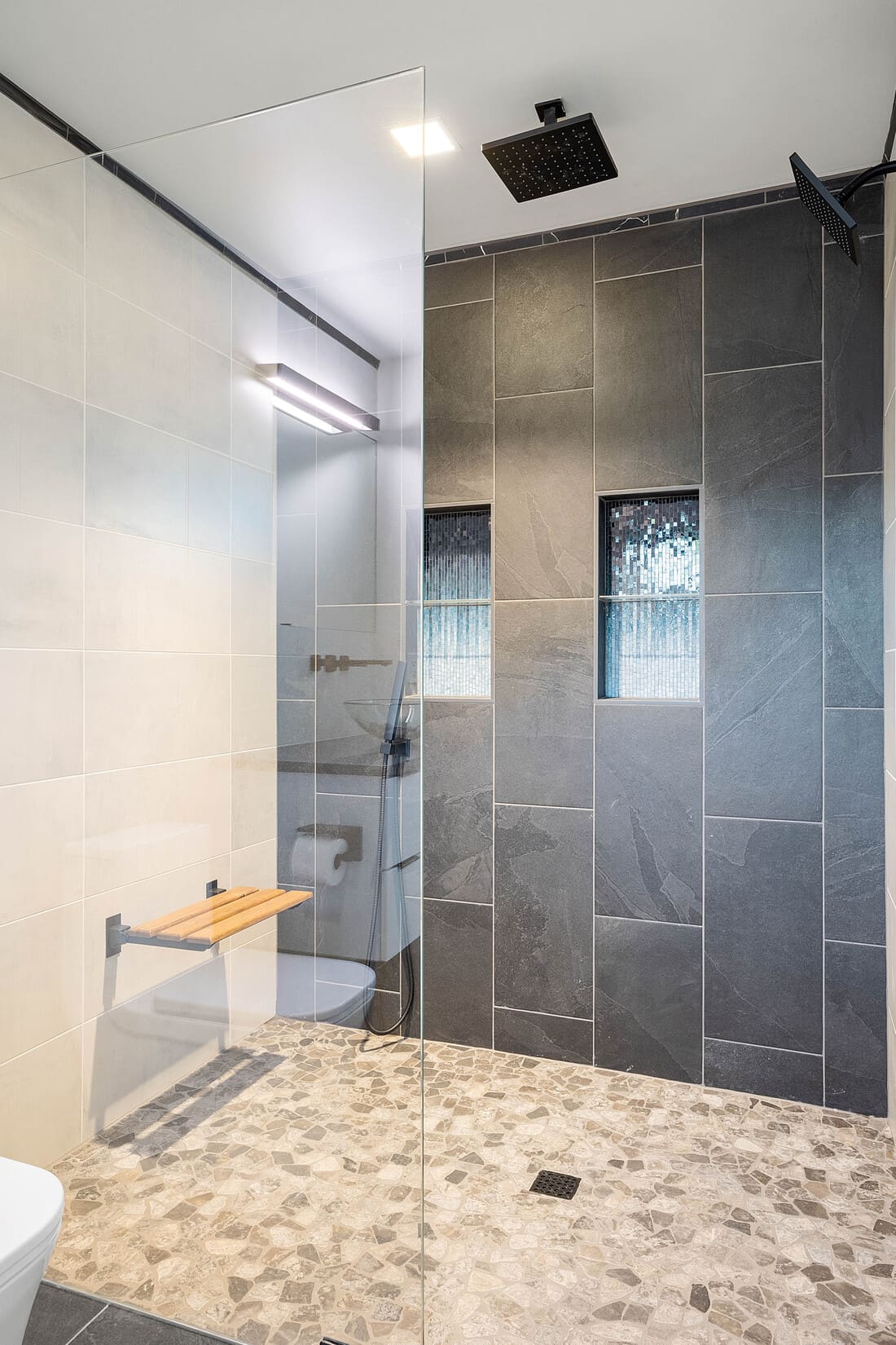 Luxury walk-in shower with vertical large format wall tiling and built-in bench & shelving 