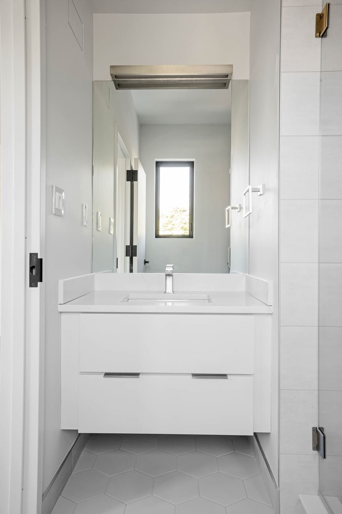View of sink in high-end custom bathroom with white hexagonal floor tiling